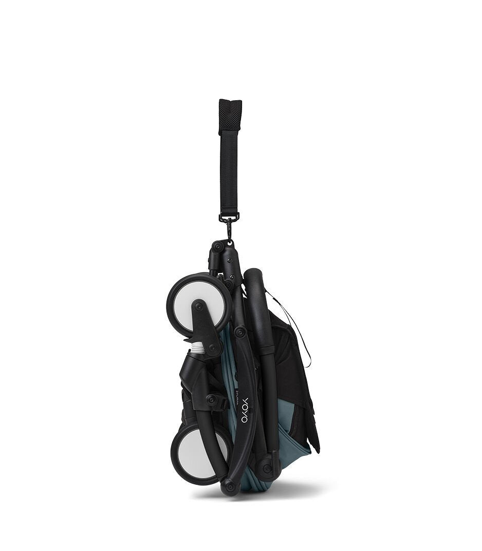 Passeggino Stokke YOYO³ ripiegato ultracompatto, telaio nero e seduta verde acqua: chiusura salvaspazio con una mano